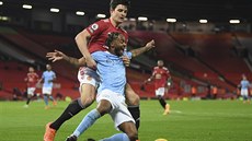 Raheem Sterling (vpravo) z Manchesteru City padá k zemi, zezadu ho drí Harry...