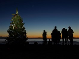 Lidé pi zimním slunovratu u vánoního stromu pozorují konjunkci planet...