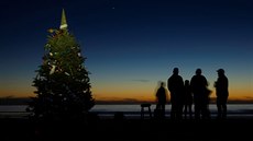 Lidé pozorují pi zimním slunovratu u vánoního stromu konjunkci planet...