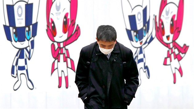 Japonec v roušce prochází kolem billboardu s Miraitowou a Someitym, maskoty olympijských her v Tokiu. (24. prosince 2020)