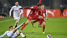 Thomas Müller (v červeném) z Bayernu se v zápase s Mönchengladbachem vyhýbá...