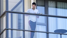 Novak Djokovi sleduje své píznivce z balkónu bhem karantény v Adelaide.