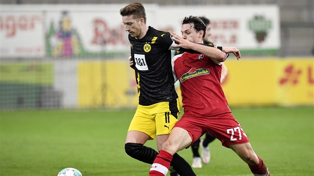 Nicolas Höfler (vpravo) z Freiburgu se snaží zastavit unikajícího Marca Reuse z Dortmundu.