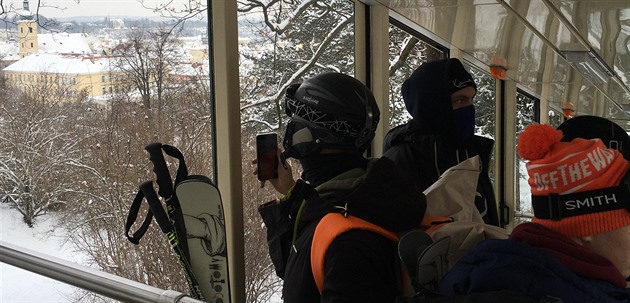Mladí lyžaři a snowboarďáci jedou lanovkou na Nebozízek. Za chvíli pojedou po...