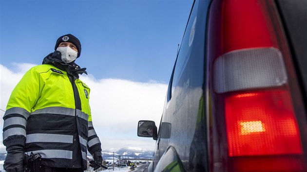 Policista kontroluje řidiče automobilu u obce Dolní Branná na hranici okresů Trutnov a Semily. Na základě vládního nařízení je kvůli šíření covidu-19 okres Trutnov uzavřený. (13. února 2021)