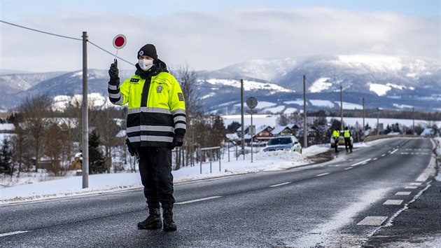 Policista kontroluje řidiče automobilu u obce Dolní Branná na hranici okresů Trutnov a Semily. Na základě vládního nařízení je kvůli šíření covidu-19 okres Trutnov uzavřený. (13. února 2021)