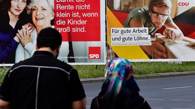Žena s muslimským šátkem jde kolem německých  volebních plakátů. (23. srpna 2017)