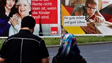 Žena s muslimským šátkem jde kolem německých  volebních plakátů. (23. srpna...