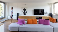 Obývacímu pokoji dominuje velká sedačka s barevnými opěrkami a polštáři.