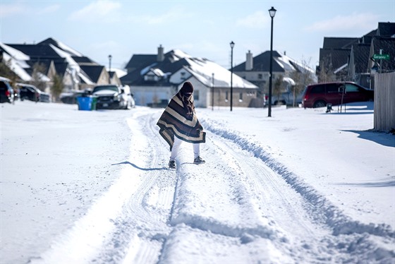 Muž prochází zmrzlou ulicí v texaském městě Pflugerville. (15. února 2021)