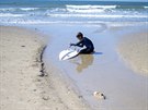 Mladý surfa istí své prkno od zbytk ropy