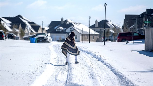 Muž prochází zmrzlou ulicí v texaském městě Pflugerville. (15. února 2021)