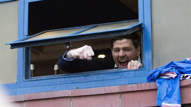 Steven Gerrard, trenér skotských Rangers, vykukuje z kabiny na ulici, kde fanoušci slaví zisk titulu.
