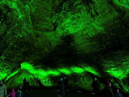 Lidé navštěvují Gutmanovu jeskyni nasvícenou stylově zeleně v lotyšské...