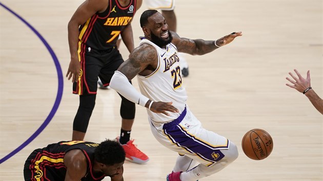 LeBron James (v blm) z LA Lakers pad zrann po stetu se Solomonem Hillem z Atlanty, sleduje je Rajon Rondo.