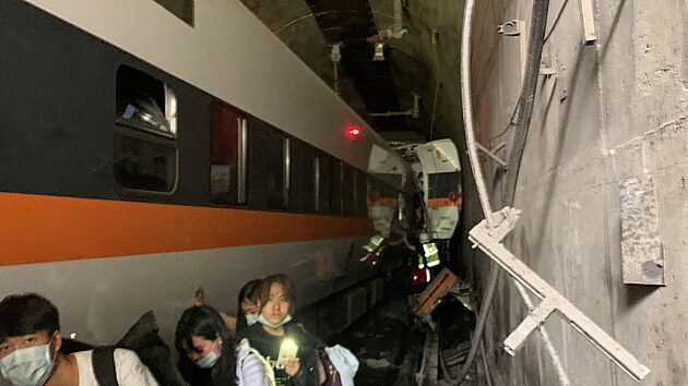 Lid po nehod odchzeli podl vlaku tunelem pry. Vagony od ptho a do osmho vozu byly nrazem deformovan a stovaly zchrann prce. (2. dubna 2021)
