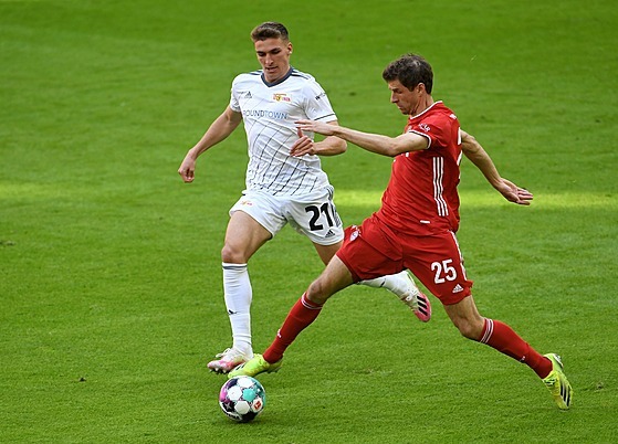 Thomas Müller (vpravo) z Bayernu Mnichov drí balon, ze strany ho napadá...