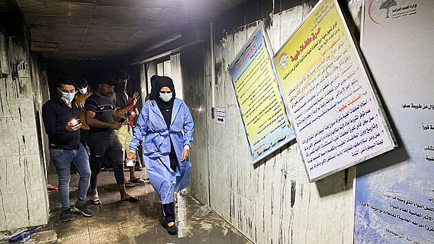 Zdravotníci a další lidé prochází troskami nemocnice v Bagdádu, ve které propukl požár. (25. dubna 2021)