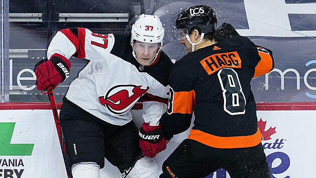 Pavel Zacha (vlevo) z New Jersey Devils a Robert Hagg z Philadelphia Flyers bojují u mantinelu.
