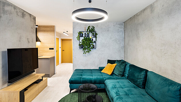 Stěny obývacího pokoje vyhladila betonová stěrka. Symbolem plynoucí energie je kruh, proto se tvar opakuje stejně jako smaragdově zelená barva.
Pohovka XXX Lutz, stolky Kare Design.