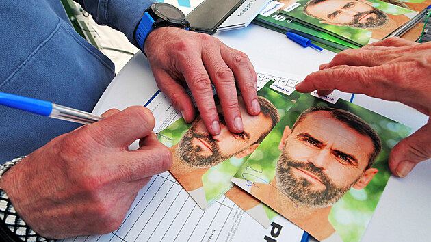 Robert lachta v rmci volebn kampan podepisuje karty se svm portrtem. (28. dubna 2021)
