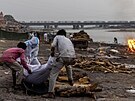Indové pálí tla obtí covidu-19 na behu eky Gangy. (6. kvtna 2021)