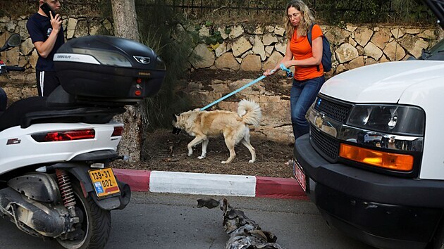ena se psem jde kolem pozstatku rakety, kterou z Psma Gazy na Jeruzalm vypustilo palestinsk radikln hnut Hams. (10. kvtna  2021)