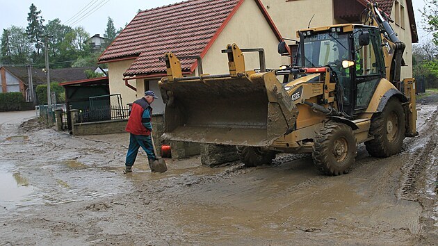 Lidé z ulice Ke Kovárně v Šilheřovicích na Hlučínsku podruhé ve dvou dnech uklízejí následky bleskové povodně. (14. května 2021)