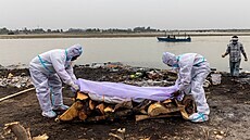 Indové pálí těla obětí covidu-19 na břehu řeky Gangy. (6. května 2021)