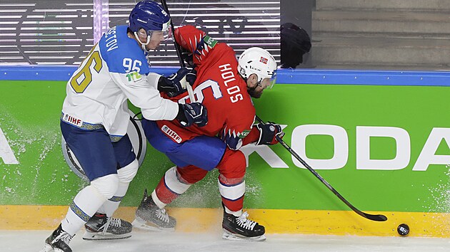 Kazašský hokejista Alichan Asetov (vlevo) napadá u mantinelu norského kapitána Jonase Holose.