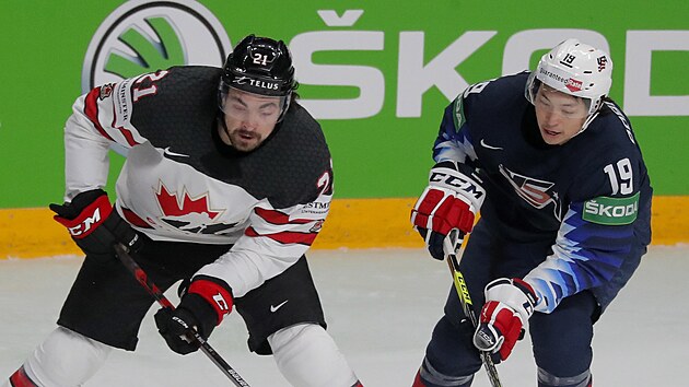 Kanadský hokejista Nick Paul si pokrývá kotouč před americkým soupeřem Jasonem Robertsonem.