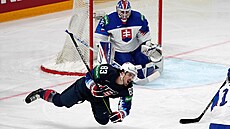Slovenský branká Adam Húska sleduje, jak americký hokejista Conor Garland padá...