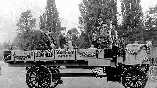Pětitunka Daimler v době mezinárodní výstavy v Paříži v roce 1898. První muž zleva je Gottlieb Daimler (ostatně na korbě to má napsáno) a čtvrtý muž zleva je Wilhelm Maybach. Také můžeme říci, že to jsou na fotografii jediní dva pánové v buřinkách, totožnost jejich sousedů v cylindrech neznáme.