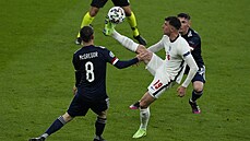 Angličan Mason Mount si špičkou zpracovává míč mezi dvěma skotskými fotbalisty.