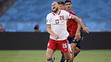 Polský fotbalista Tymoteusz Puchacz padá po faulu od Marcose Llorenteho ze...