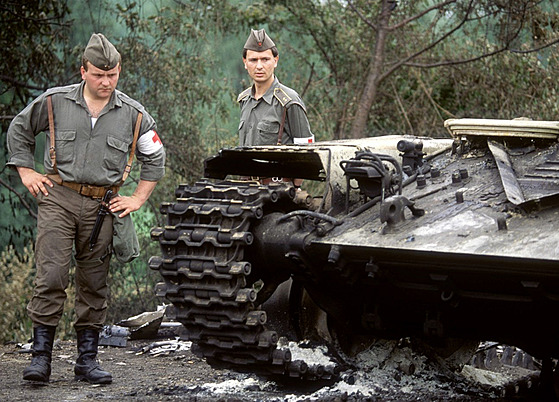 BOJE Jugoslávtí vojáci prohlíejí trosky ohoelého tanku po bojích na...