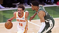 Trae Young z Atlanty se tlaí pes Janise Adetokunba z Milwaukee.