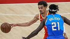 Trae Young z Atlanty útoí proti Milwaukee, brání ho Jrue Holiday.