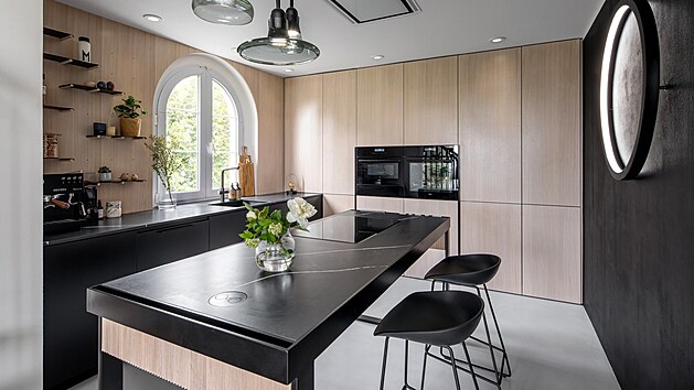Kuchyňskou linku navrhli architekti a využili kontrastu dekoru dřeva a černé. Závěsná svítidla jsou od české sklářské značky Brokis v designu Lucie Koldové.