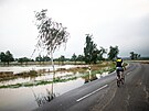 Cyklista jede po zaplavené silnici v nmeckém Kircheimu (15. ervence 2021)