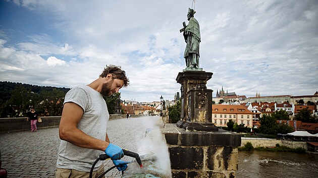 Restaurátor Jakub Tlučhoř od ranních hodin pracuje na Karlově mostě na odstranění graffiti nápisu. (11. července 2021)