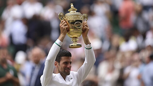 Dojatý Novak Djokovič zvedá nad hlavu trofej pro vítěze Wimbledonu.