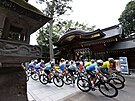 Cyklisté v silniním závod míjejí svatyni s názvem Okunitama.