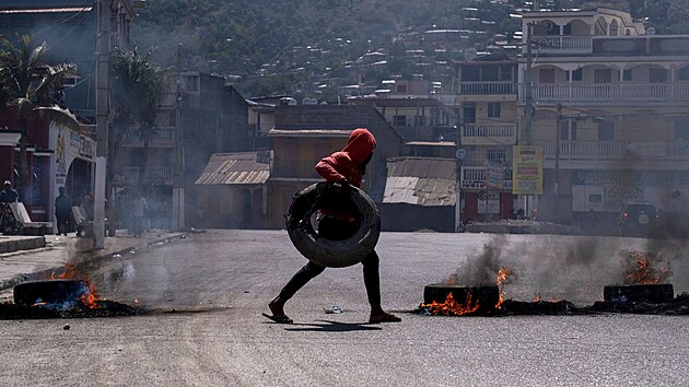Demonstrant nesl pneumatiku, kterou nsledn zaplil bhem demonstrace na Haiti. (22. ervence 2021)
