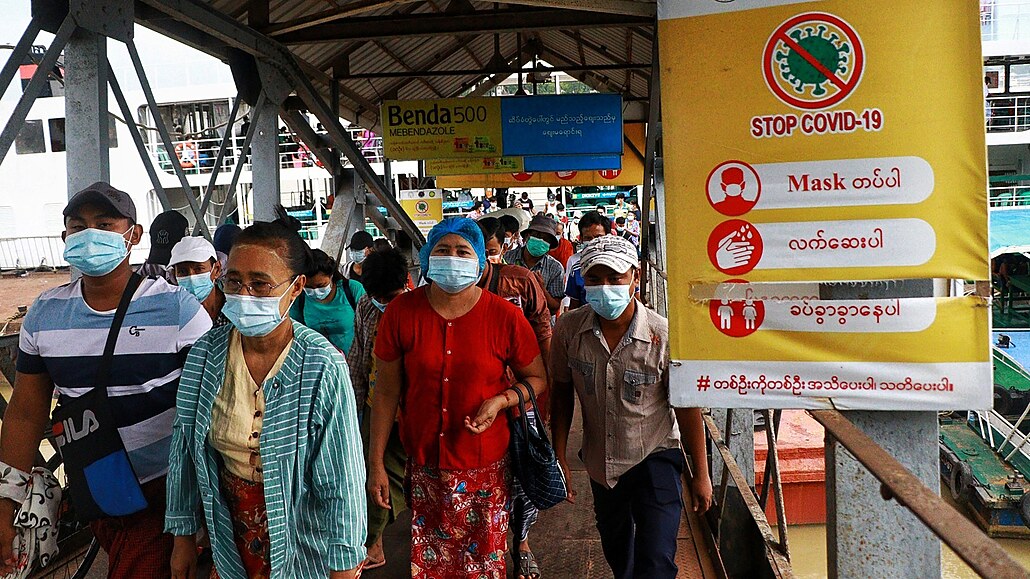Cestující v Myanmaru prochází kolem plakátu s heslem Zastavte COVID-19. (27....