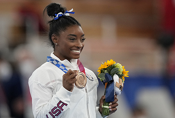 Simone Bilesová pyn ukazuje olympijský bronz z kladiny.