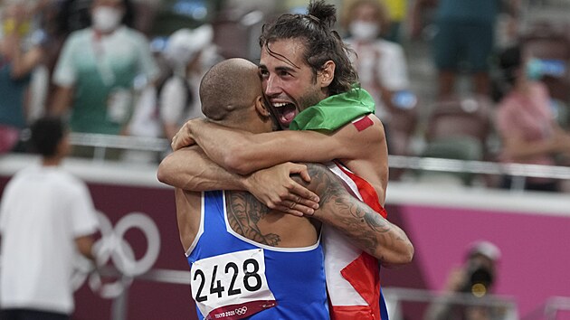 Gianmarco Tamberi objm vtze sprintu na 100 metr Lamonta Jacobse. (1. srpna 2021)