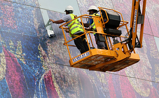 Dělníci ze stěny stadionu Camp Nou v Barceloně odstraňují obří plakáty s Lionel...
