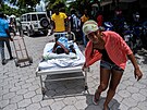 Lidé pesouvají zrannou enu do nemocnice ve mst Les Cayes. (16. srpna 2021)