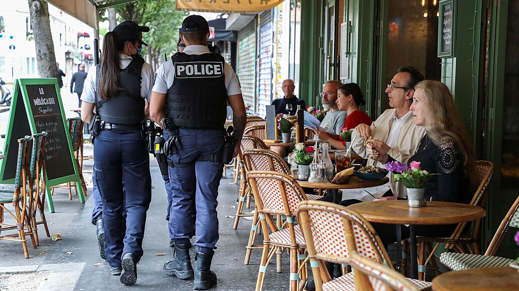 Policisté v Paříži kontrolují covid pasy lidí v kavárně.